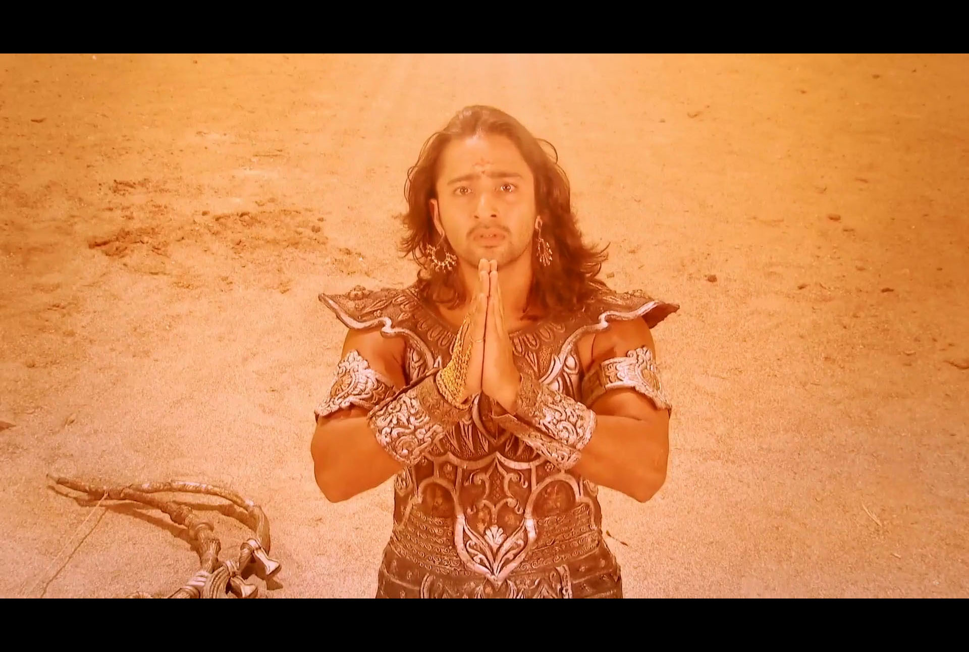 Shaheer Sheikh plays the warrior prince Arjun in the Vishwaroop scene of the Bhagavad Gita in Star Plus Mahabharat (2014), in which Shri Krishna reveals to Arjun the supreme knowledge of his universal form. Arjun is seen kneeling on a dusty battlefield in full armour, his bow cast aside and his hands pressed together in prayer, looking upward in apprehension, reverence and awe.