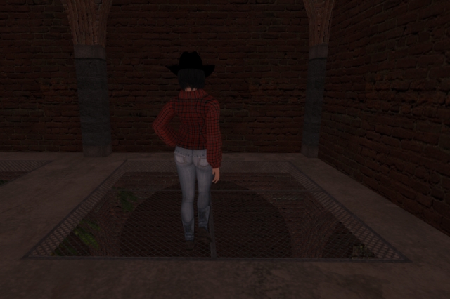 Me in the same Western-style outfit as in the previous post, standing on a floor grating in a building; there's another floor below