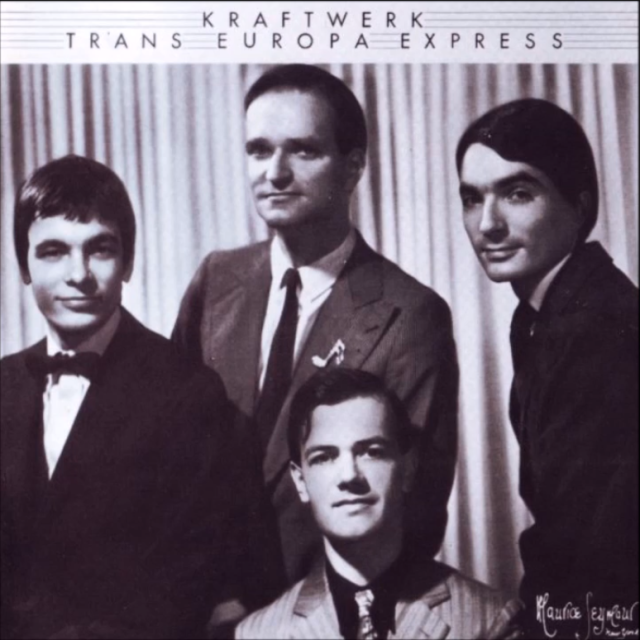 screenshot des lp-covers von kraftwerks "trans europa express". foto in schwarz-weiß, die vier mitglieder in anzügen mit schlips. alle lächeln leicht. längs gestreifter hintergrund, vielleicht ein vorhang.  