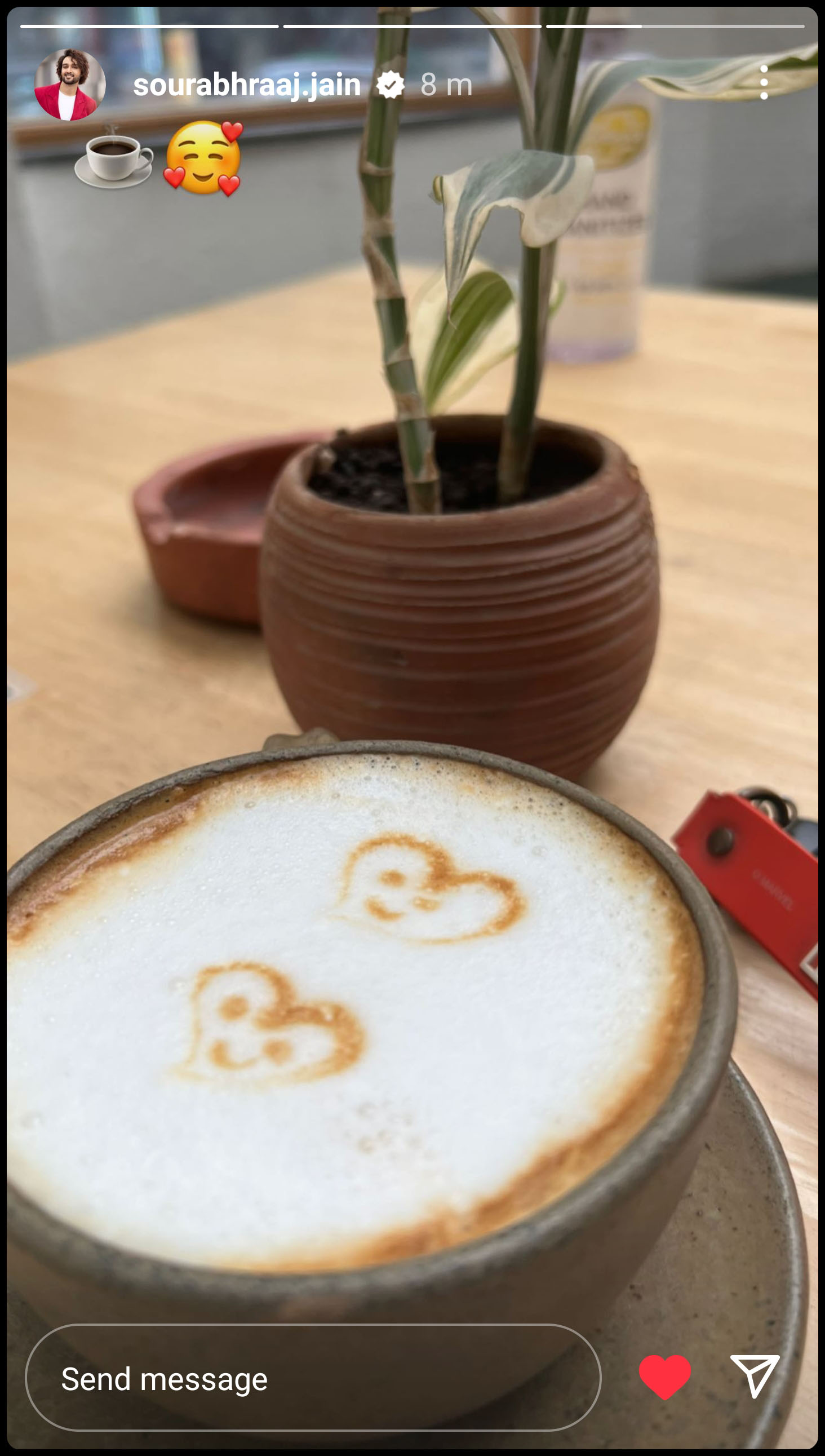 A photograph of a cup of coffee with two hearts, each with smiling faces, drawn in the foamed milk, posted as an Instagram story by Sourabh Raaj Jain. 