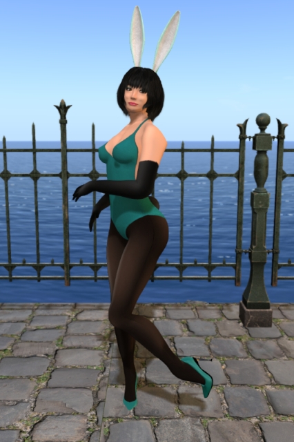 Self-portrait, taken at Paris, Creative Landform. My outfit has changed: I'm still wearing the same teal bathing-suit as a bodysuit/leotard, but now over a pair of darker black sheer and seamed tights and with teal pumps. I've turned myself to my right to show the black bunny tail which is now attached to the bathing-suit, and my left foot is raised behind me. Also, I'm wearing a pair of long black gloves now. The white and cyan bunny ears, the teal eyeshadow, the black eyeliner and the fuchsia lipstick are still the same. Right behind me, there is a wrought iron fence which separates the cobblestone promenade I'm standing on from the ocean in the background.