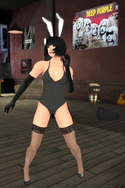 Dancing in my raciest bunny outfit so far, a variant of the "black bunny" with white and black bunny ears, a black bathing-suit, black gloves, black stockings and black pumps, combined with grey eyeshadow, black eyeliner and red lipstick; the items in the background include a poster based on the cover of the Deep Purple album In Rock, a set of congas, a sofa and a cigarette machine