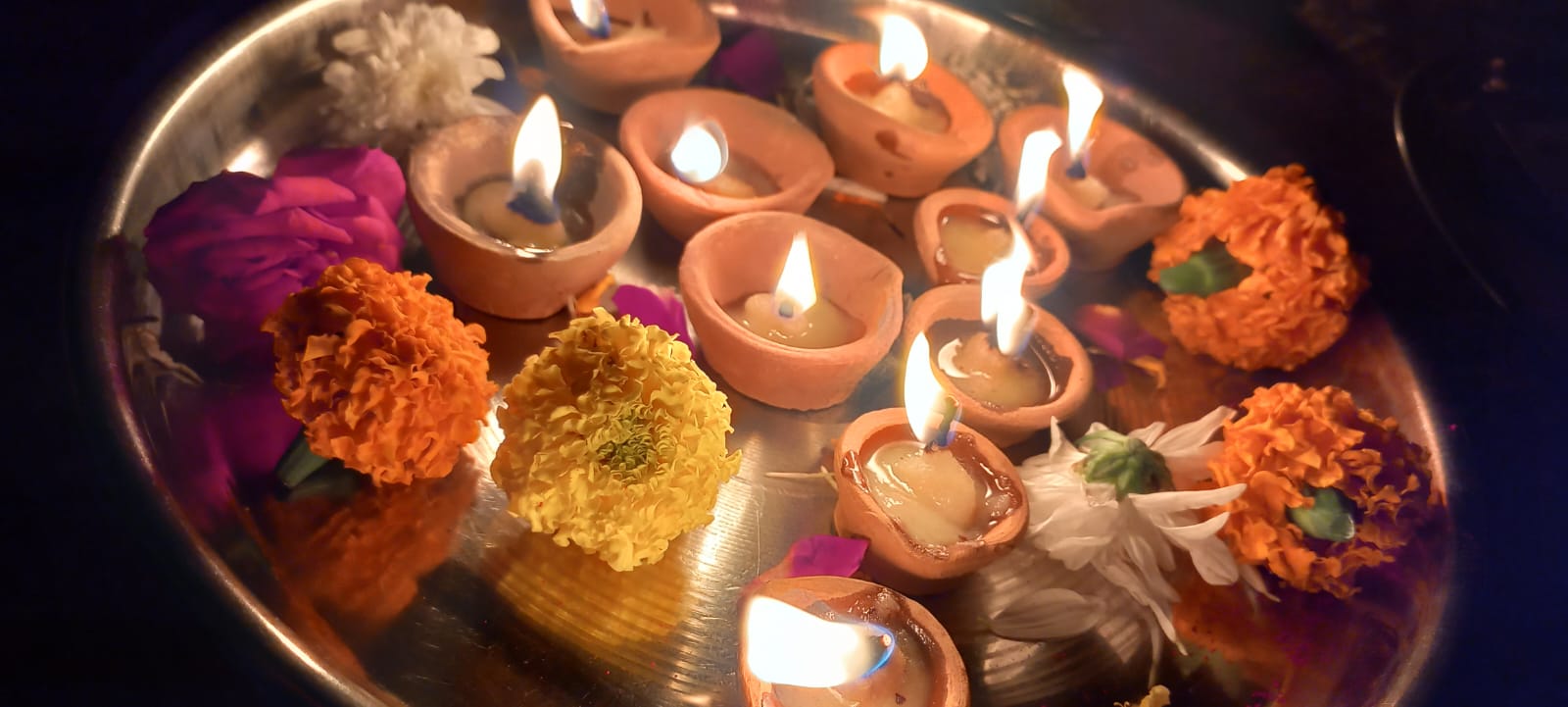 Lit ghee lamps are carried on a silver puja thali (ceremonial plate for ritual worship) decorated with chrysanthemums for the Tulsi Vivah festival on Nov. 5, 2022.